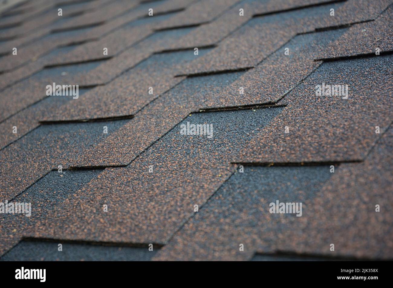 Kupfer, braun architektonischen, dimensionalen Asphalt Dachschindeln Hintergrund. Nahaufnahme eines Daches, das mit braunen Asphaltschindeln bedeckt ist. Stockfoto