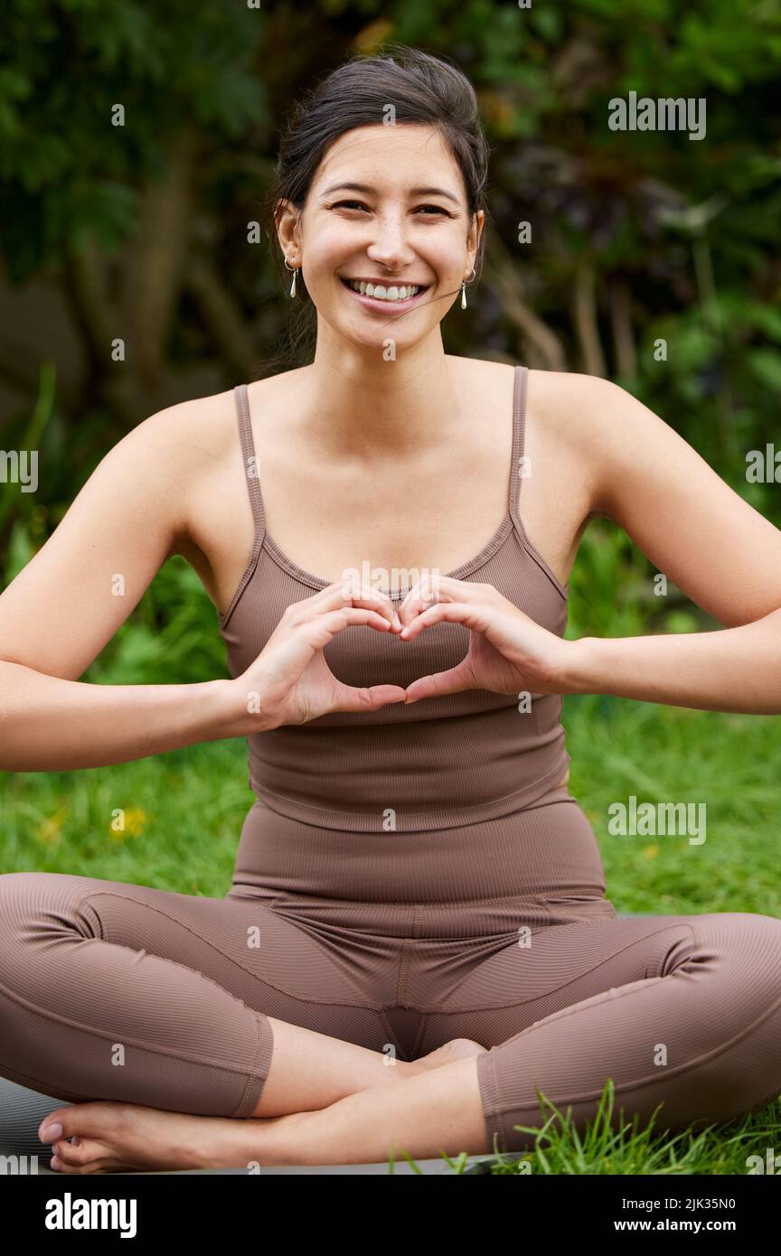 Gute Gesundheit ist eine große Nahrung für Körper und Seele. Porträt einer jungen Frau, die mit ihren Händen eine Herzform beim Training im Freien macht. Stockfoto