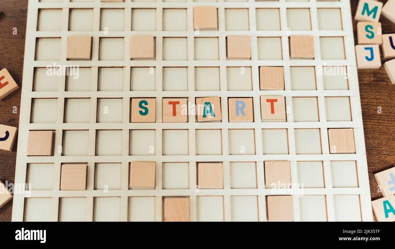 Bunte hölzerne quadratische Buchstaben schaffen einen WORTANFANG. Werbeidee. Orange, Türkis und babyblaue Buchstaben. Hochwertige Fotos Stockfoto