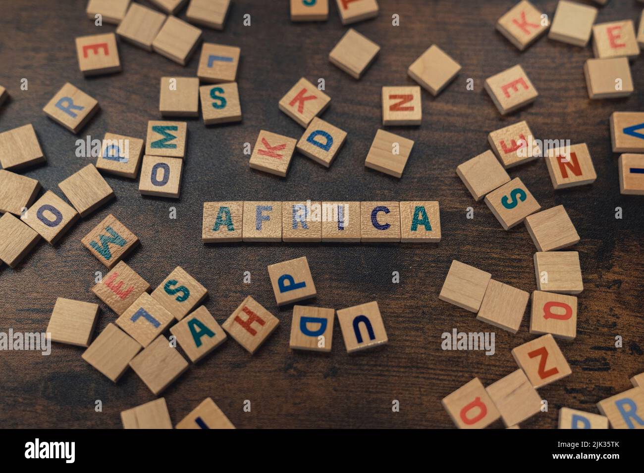 Afrika - einer der sieben Kontinente. Bunte Holzbuchstaben schaffen das Wort AFRIKA. Dunkler Holztisch als Hintergrund. Hochwertige Fotos Stockfoto