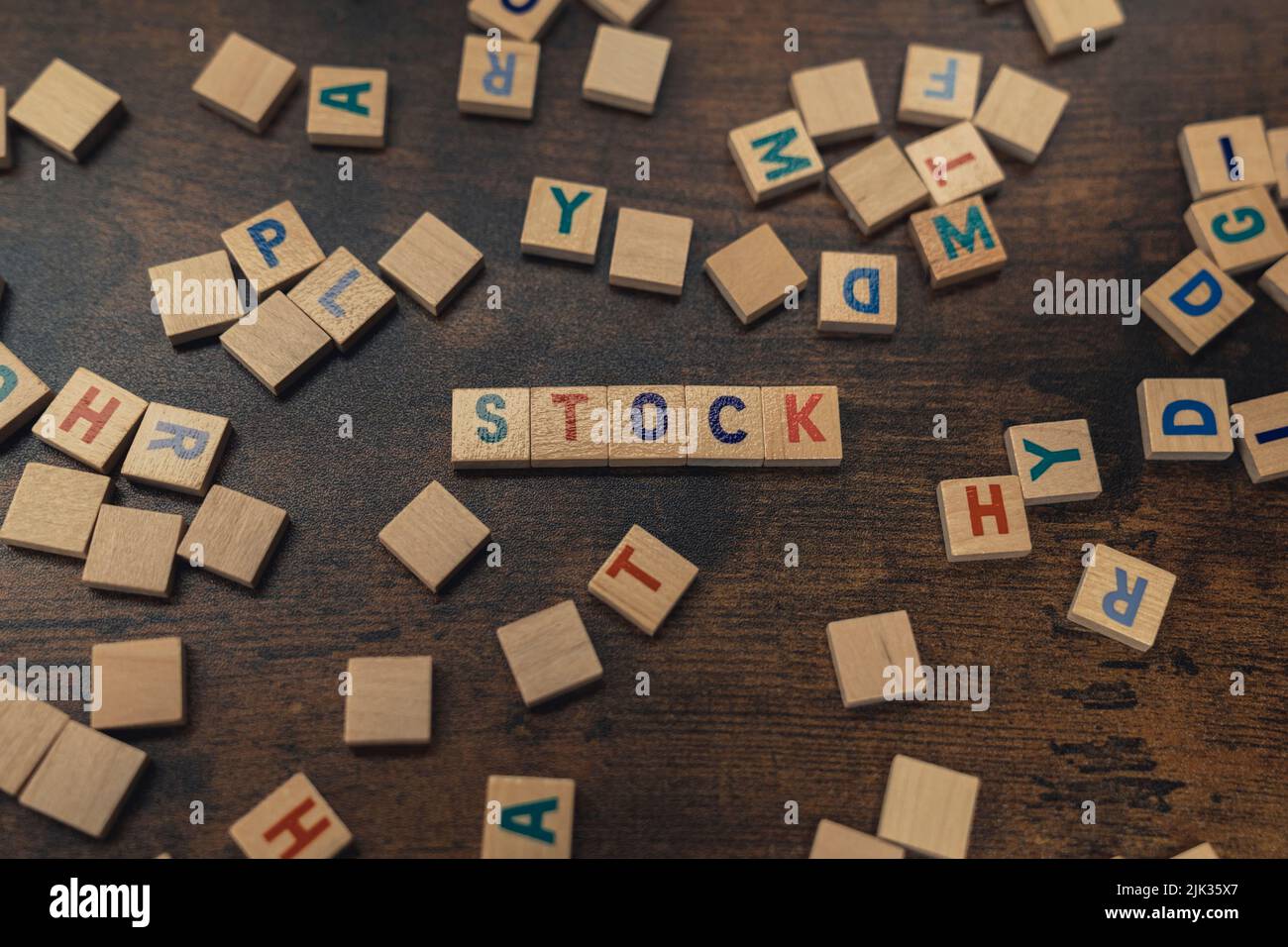 Verstreute Holzbriefe auf einem dunklen Holztisch. Bunte Buchstaben, die den WORTBESTAND erzeugen. . Hochwertige Fotos Stockfoto