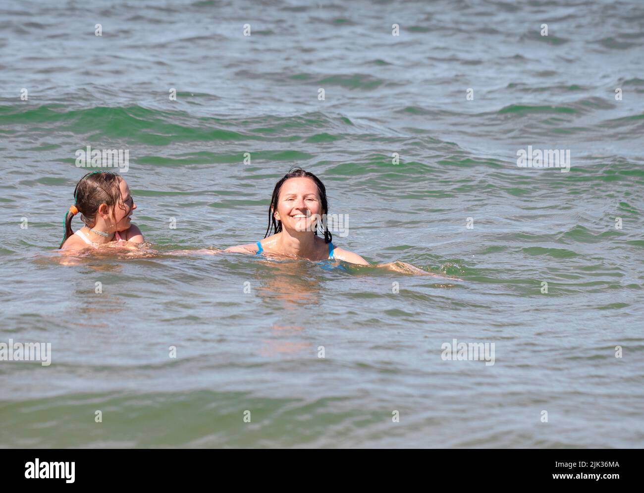 Mutter und Tochter am Strand und in den Meereswellen. Ostsee, Polen. Stockfoto
