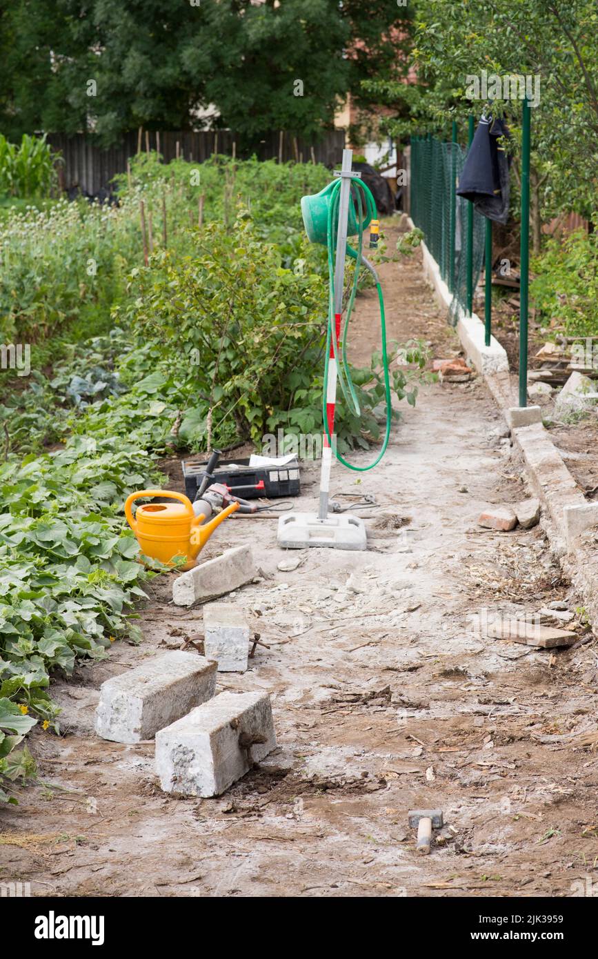 Ersetzt den alten Gartenzaun durch einen neuen. Bau neuer Maschendrahtzaun im Garten des Hauses Stockfoto