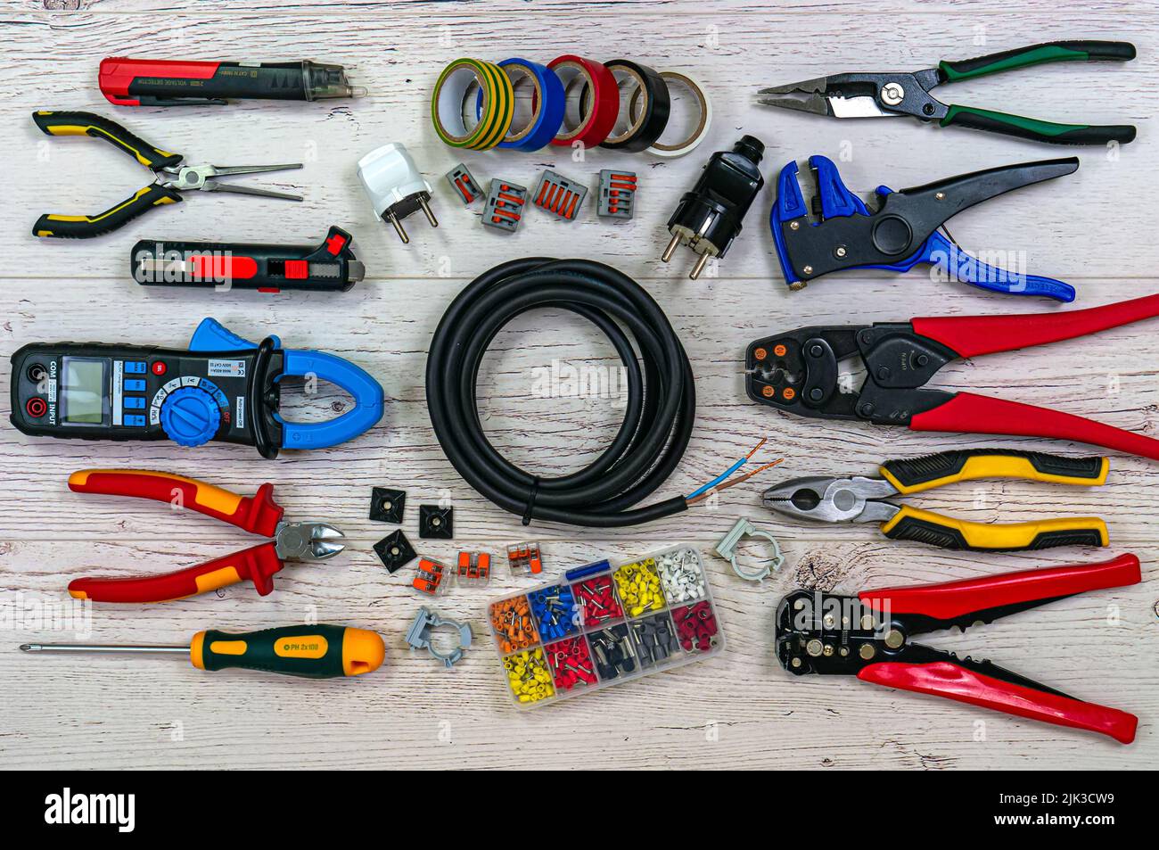 Professionelle Elektriker Werkzeuge und elektrische Komponenten auf leichten Holzbrettern. Zangen, Abisolierer, Crimper, Multimeter, Tester, Schraubendreher. Spule von Stockfoto