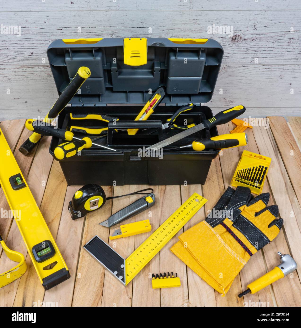 Bauinstrumente und eine Werkzeugkiste auf Holzbohlen Hintergrund. Alle Werkzeuge und eine Box mit gelben Elementen. Stockfoto