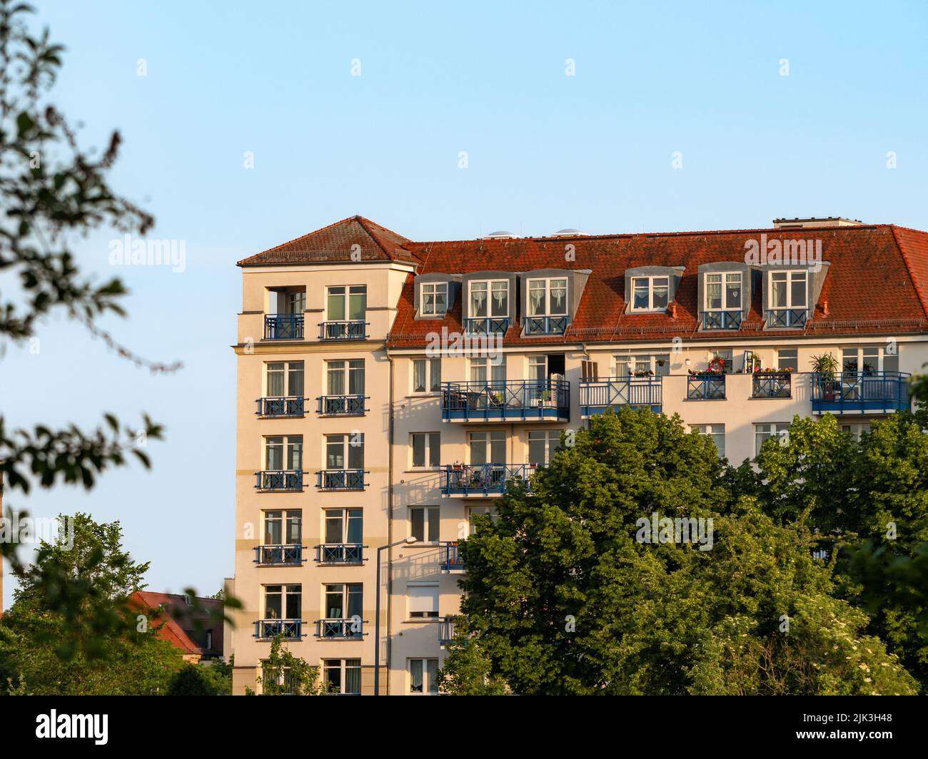 Hohes Apartmentgebäude mit vielen Balkonen an der Fassade. Architektur in der Stadt am Abend. Ein Haus im Abendlicht in Dresden. Stockfoto