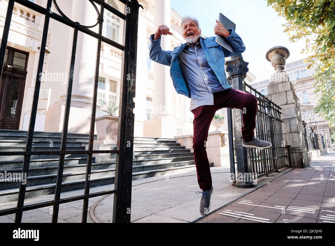 Ein glücklicher älterer Student im Umschulungsprogramm hat die Prüfung bestanden und er springt vor Freude und Glück. Stockfoto