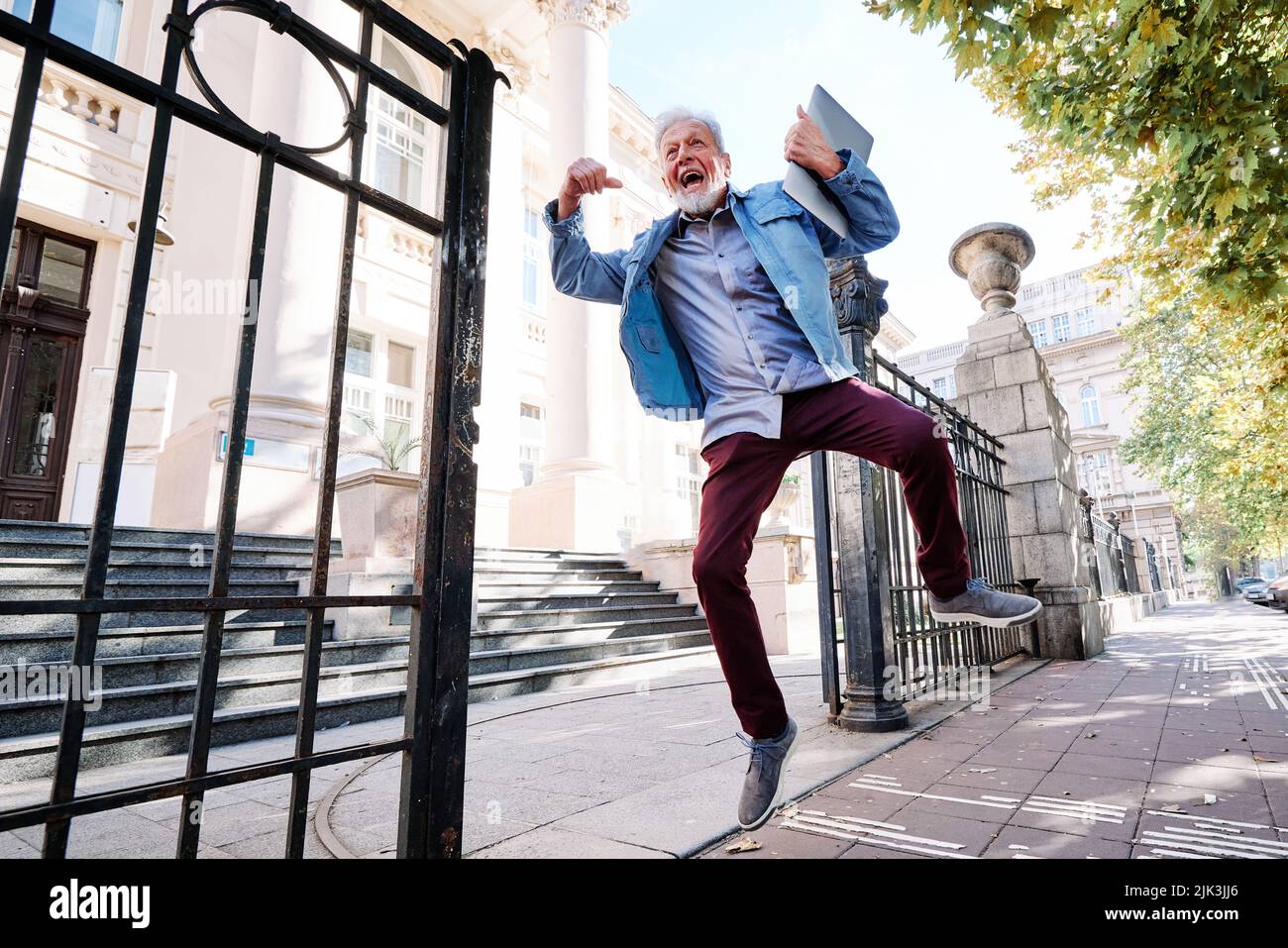 Ein glücklicher älterer Student im Umschulungsprogramm hat die Prüfung bestanden und er springt vor Freude und Glück. Stockfoto