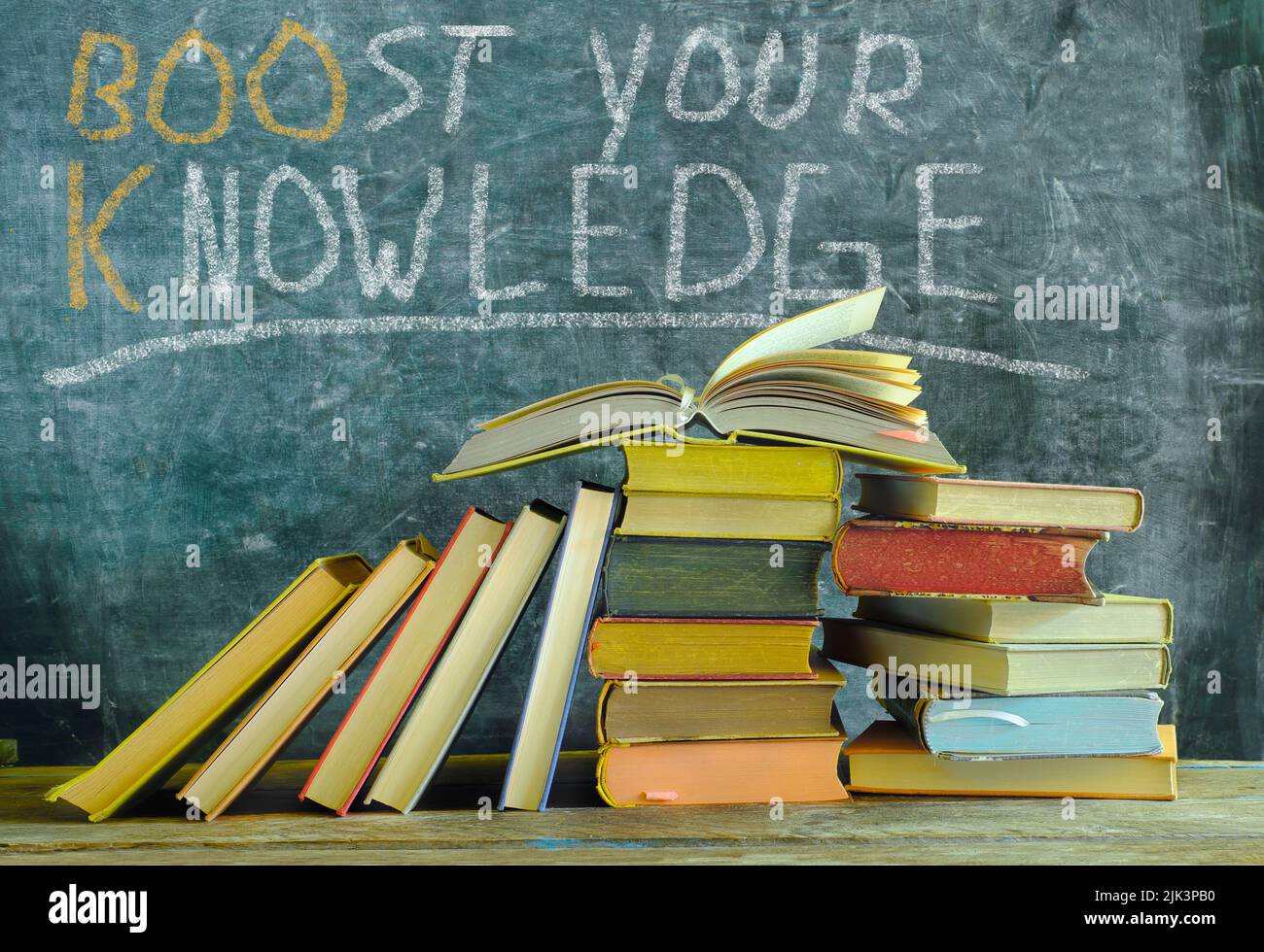 Offenes Buch vor einem schwarzen Brett mit Slogan steigern Sie Ihr Wissen, Lernen, Bildung, Home Office und Back-to-School-Konzept Stockfoto