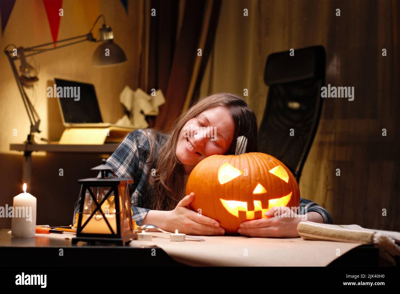 Leuchtender Kürbis für Halloween. Frau sitzt und umarmt bereit Kerze angezündet halloween Jack O Laterne Kürbis zu Hause für ihre Familie. Stockfoto