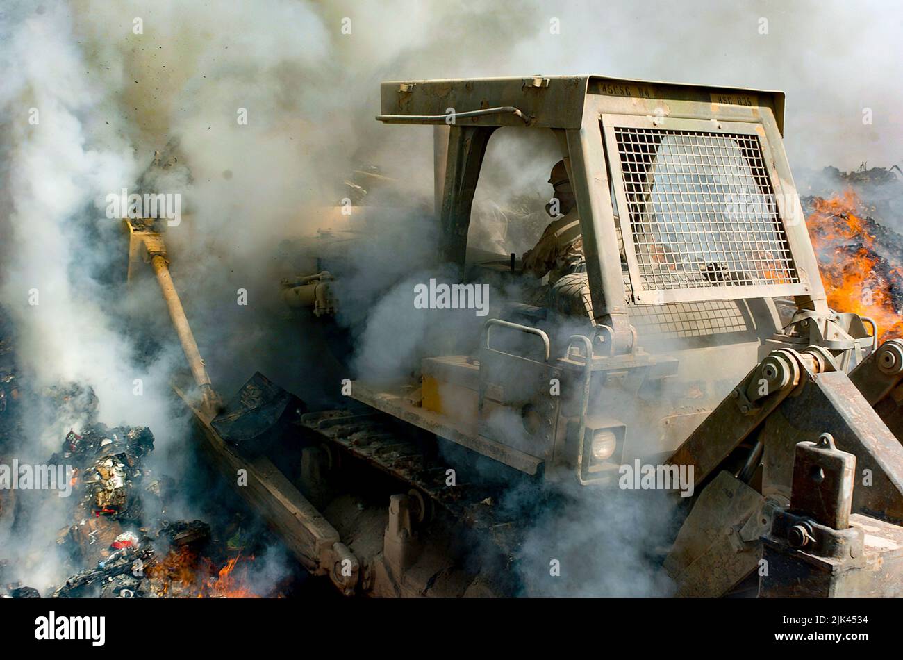 (LOGISTIKBEREICH ANACONDA, Balad, Irak) - Rauch kommt von allen Seiten als Sgt. Richard Ganske, Bataillon des Kampfingenieurs von 84., schiebt den Bulldozer tief in die Flammen der Brandgrube, um brennbare Gegenstände ständig in Flammen zu halten und sie zu entsorgen, damit sie den Posten nicht aufwirren. Bulldozer und Bagger sind die schweren Geräte, die von den 84. EN Mrd. verwendet werden, um Müll in der Brandgrube zu verwalten. Stockfoto