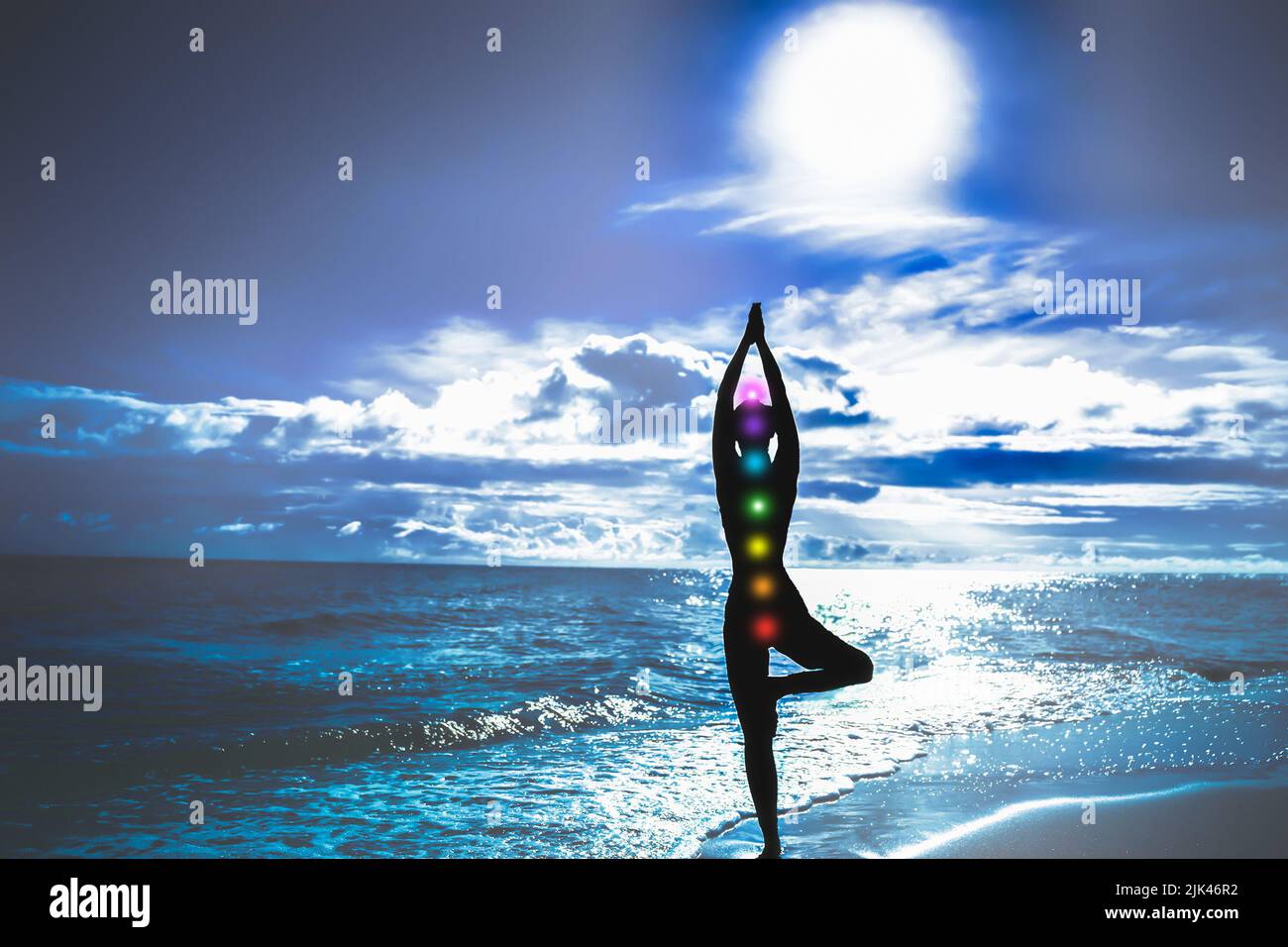 Silhouette mit Chakren. Frau in Baumhaltung auf blauem Hintergrund von Meer und Sonne. Harmonie und Yoga Konzept Stockfoto