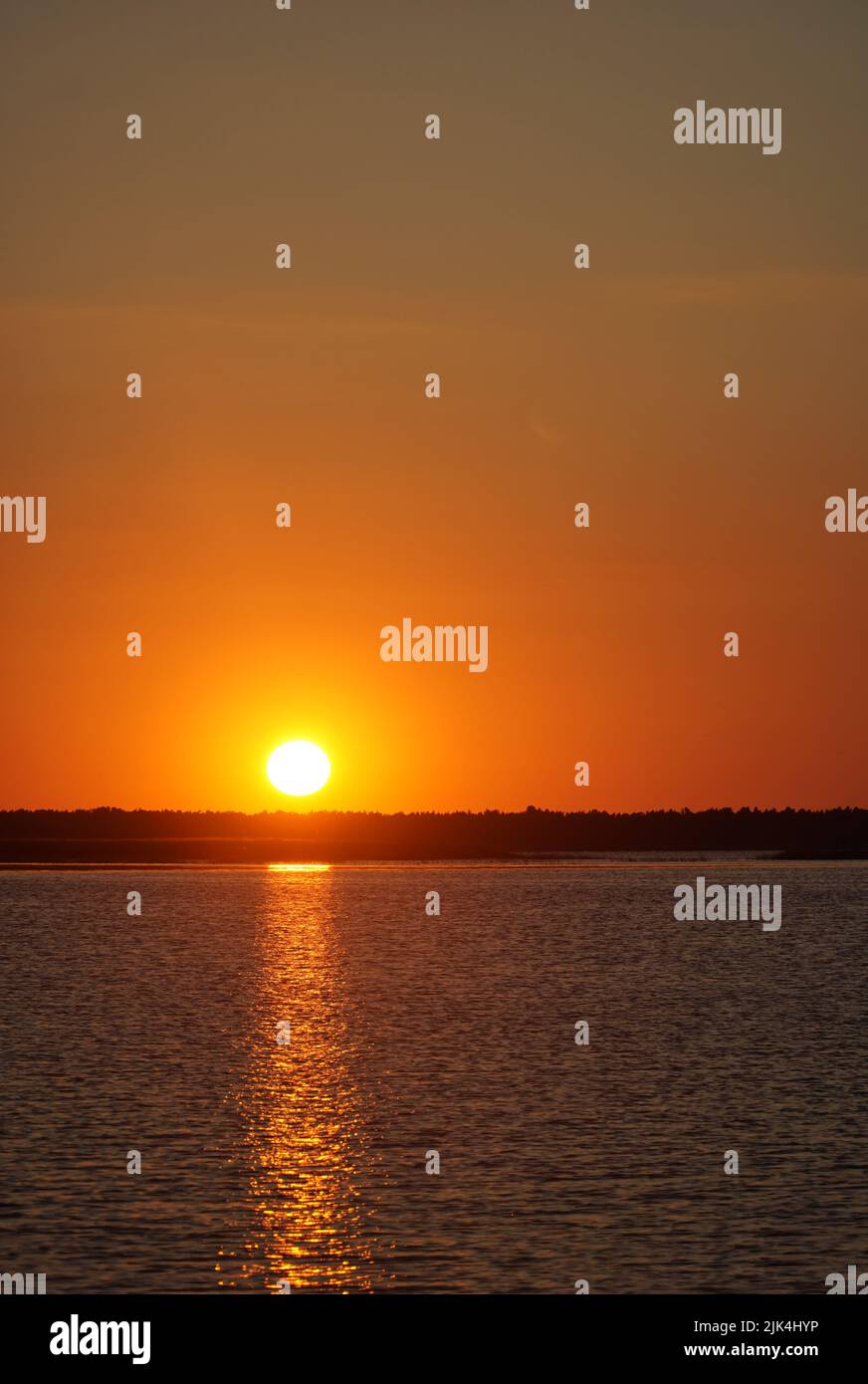 Sonnenuntergang über dem See Łebsko, Woiwodschaft Pommern, Polen. Sommerabend, klarer Himmel, Spiegelung des Lichts im Wasser. Stockfoto