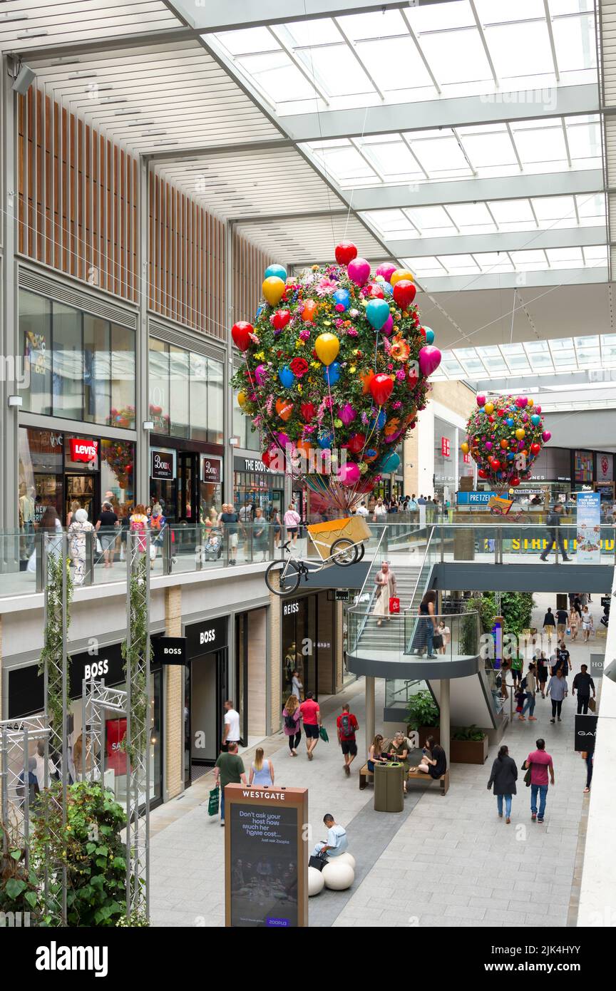 Das Innere des Westgate Shopping Centre mit Menschen, die an Einzelhandelsgeschäften vorbeilaufen, Oxford, Großbritannien Stockfoto