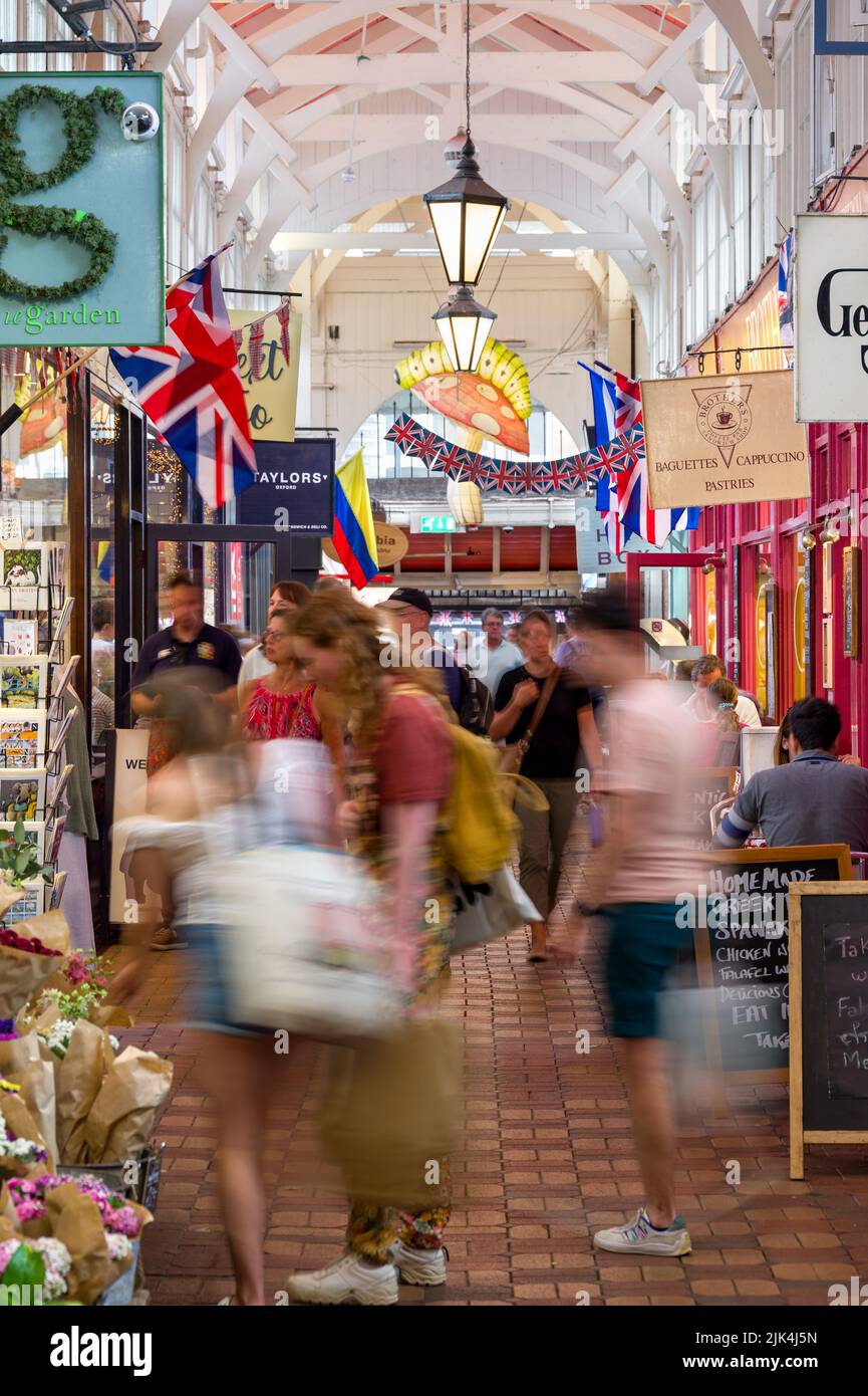Innenansicht des überdachten Marktes mit Menschen, die an Geschäften vorbeilaufen, Oxford, Großbritannien Stockfoto