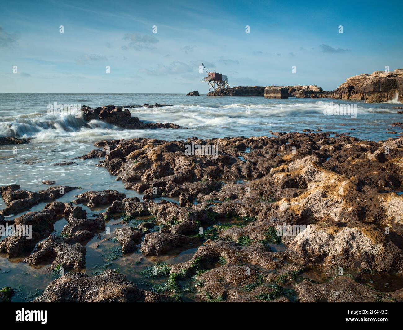 Küstenlandschaft mit Wellen des Atlantiks und felsigem Strand mit einer Fischerhütte am Horizont in Saint Palais-sur-mer, Charente Maritime, Frankreich Stockfoto