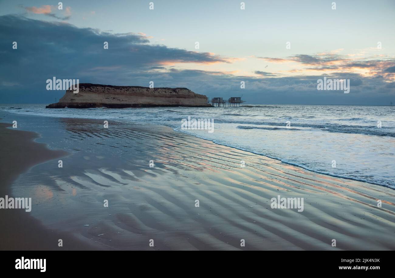 Abenddämmerung am Strand zur Blue Hour in Charente Maritime, Frankreich mit erodierter felsiger Insel am Ufer der Gironde-Mündung Stockfoto