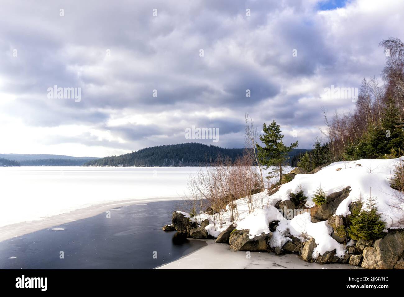 Stausee mit gefrorenem Wasser im Gebiet von Josefuv Dul am Staudamm, Izera-Gebirge, Tschechien, Europa. Dramatische Wolken am Himmel. Stockfoto