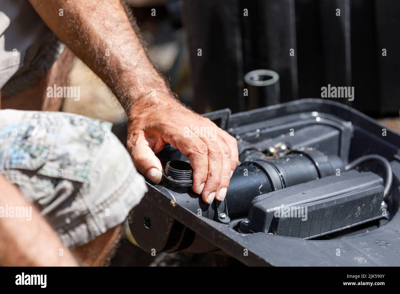 Männliche Hände reparieren ein Gartenteichfiltrationssystem Stockfoto