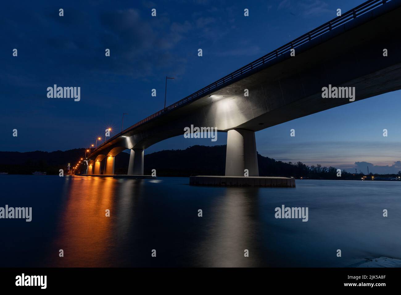 Ko Lanta Siri Lanta Brücke, von unten und beleuchtet am Abend, kurz nach Sonnenuntergang. Lange Belichtung mit Bewegungsunschärfe auf dem Wasser und Reflexionen Stockfoto