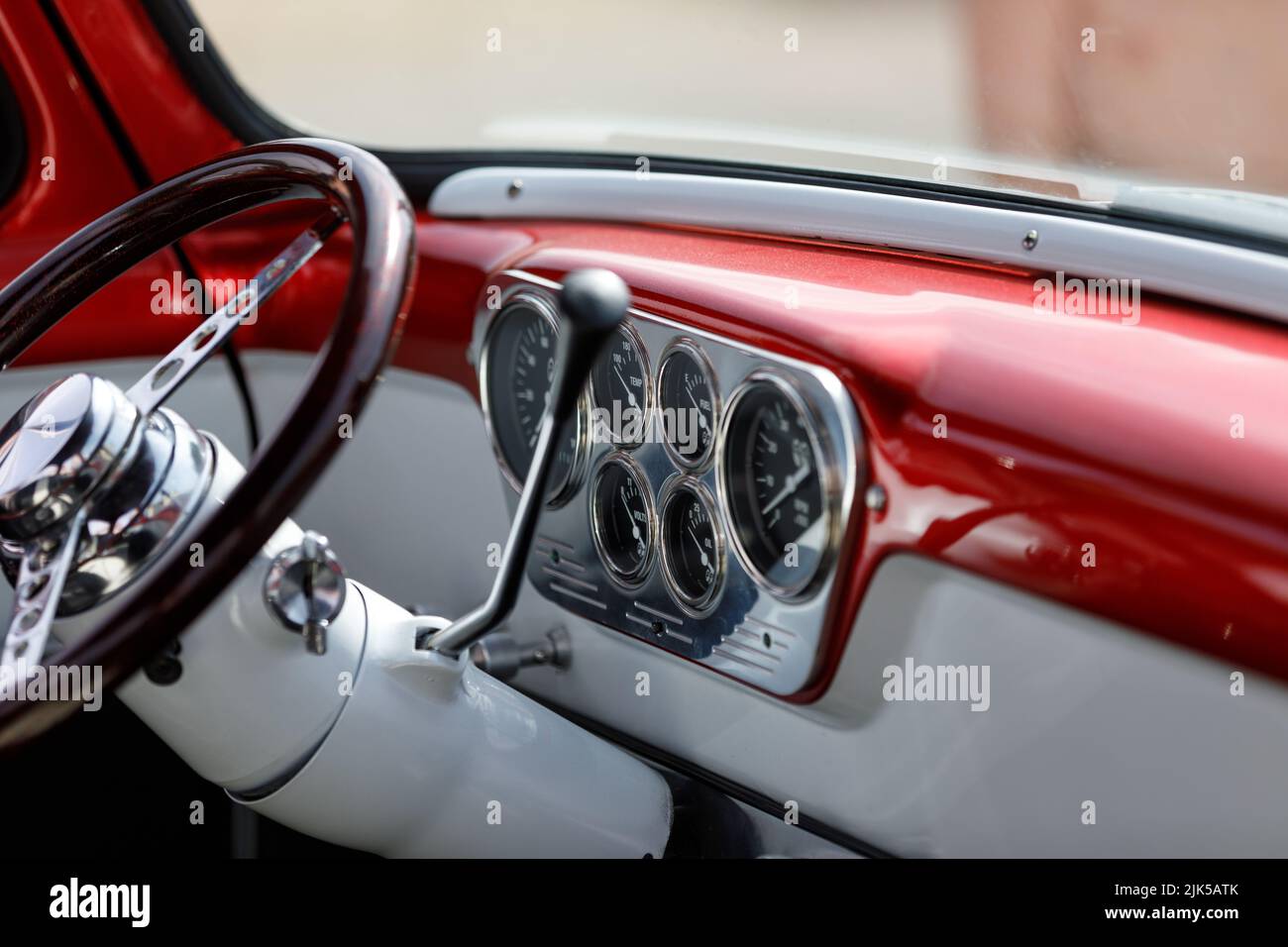 Armaturenbrett, Lenkrad und Spurführung auf einem Custom-Pick-up-Truck des Ford F100 aus den 1950er Jahren mit Edelstahlbedienfeld, Zifferblättern und rotem Metallgestelle Stockfoto