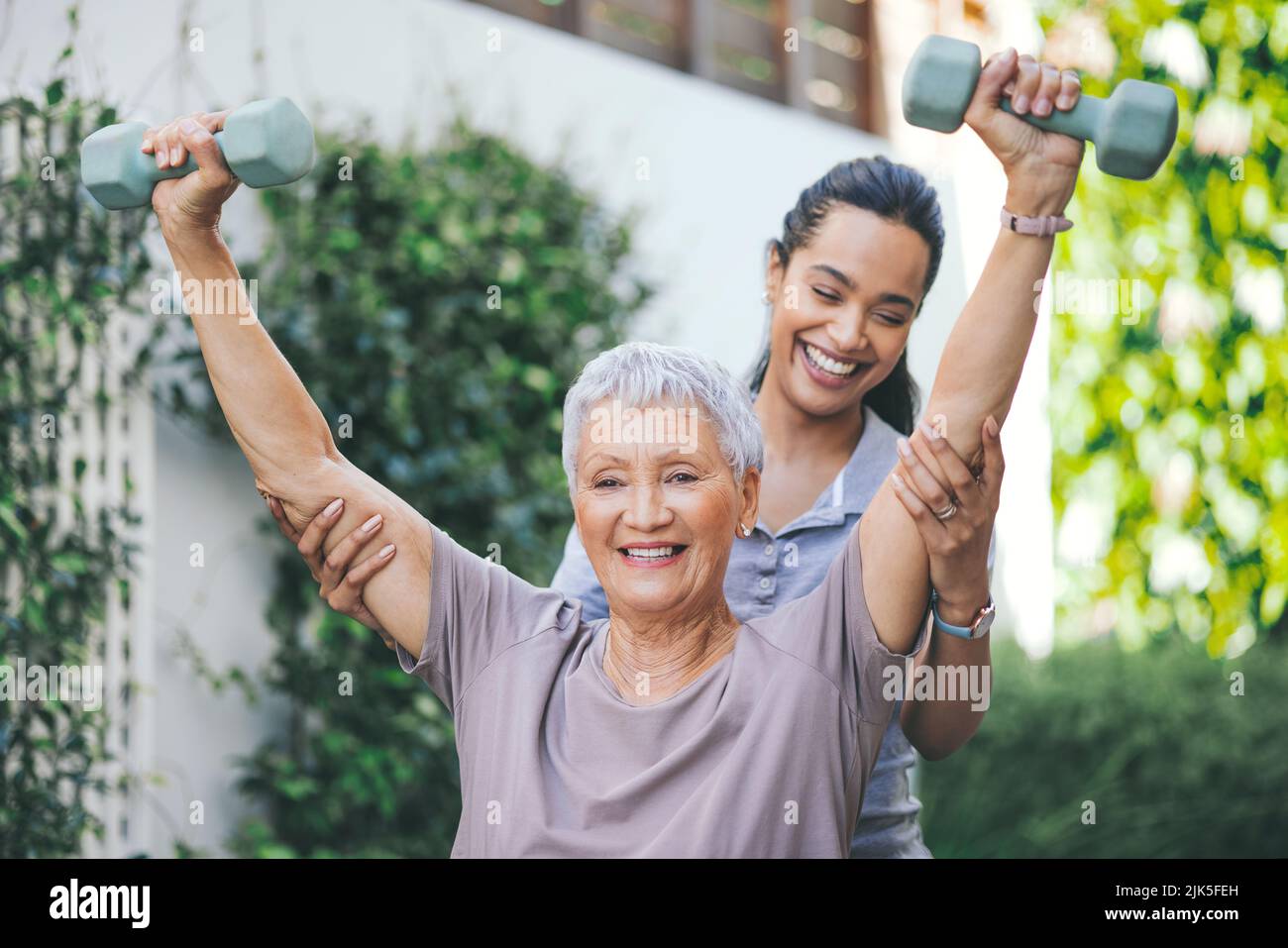 Ein Frühaufsteher fängt den Wurm. Eine ältere Frau hebt während einer Sitzung mit einem Physiotherapeuten Hanteln. Stockfoto