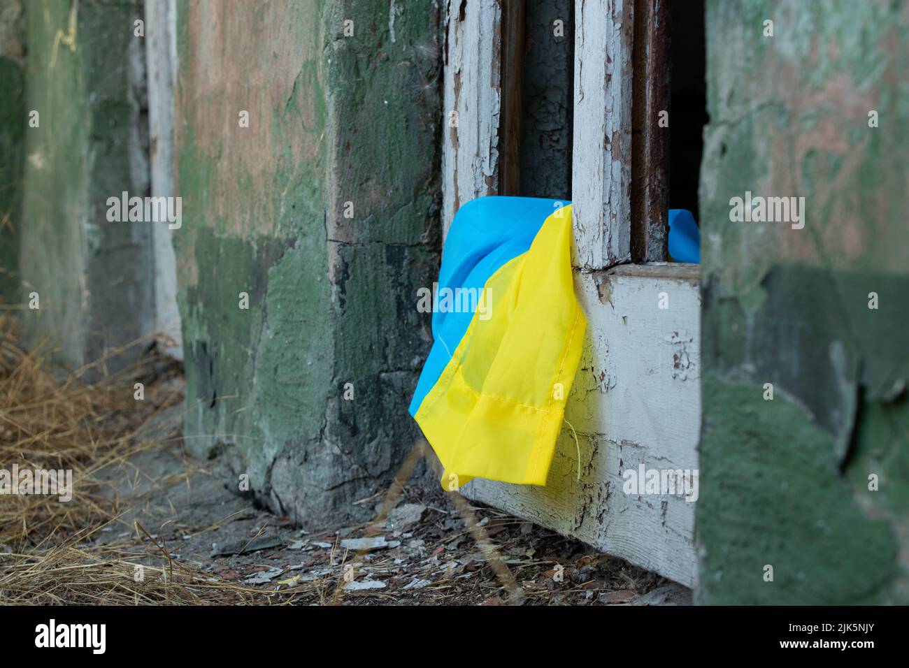 Ein zerstörtes Gebäude und eine zerbrochene Tür von der Explosion und daneben liegt die Flagge der Ukraine in der Stadt Dnepr in der Ukraine, Krieg Stockfoto