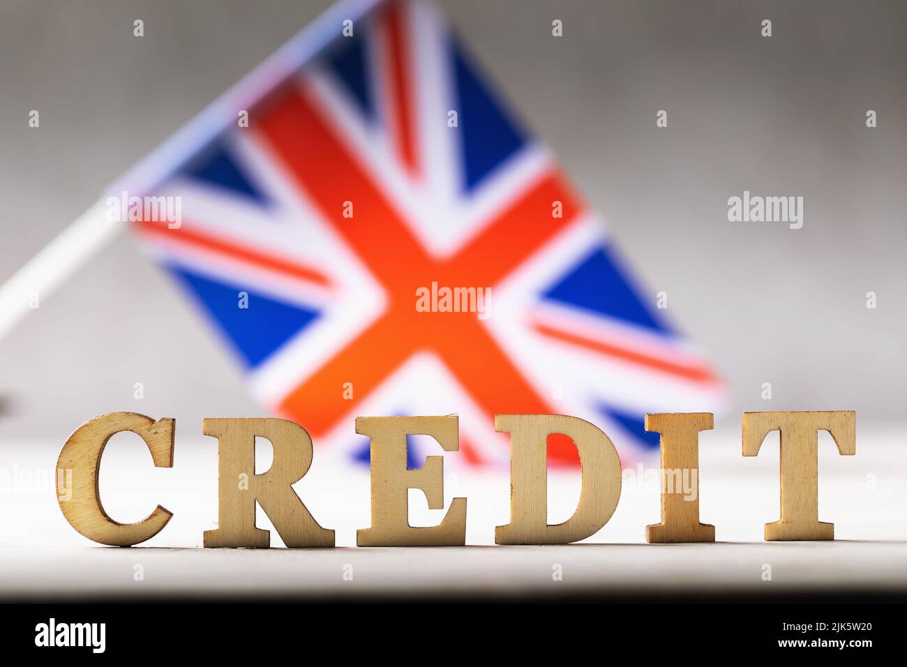 Holzbuchstaben Text und britische Flagge auf abstraktem Hintergrund, Kreditkonzept aus england Stockfoto