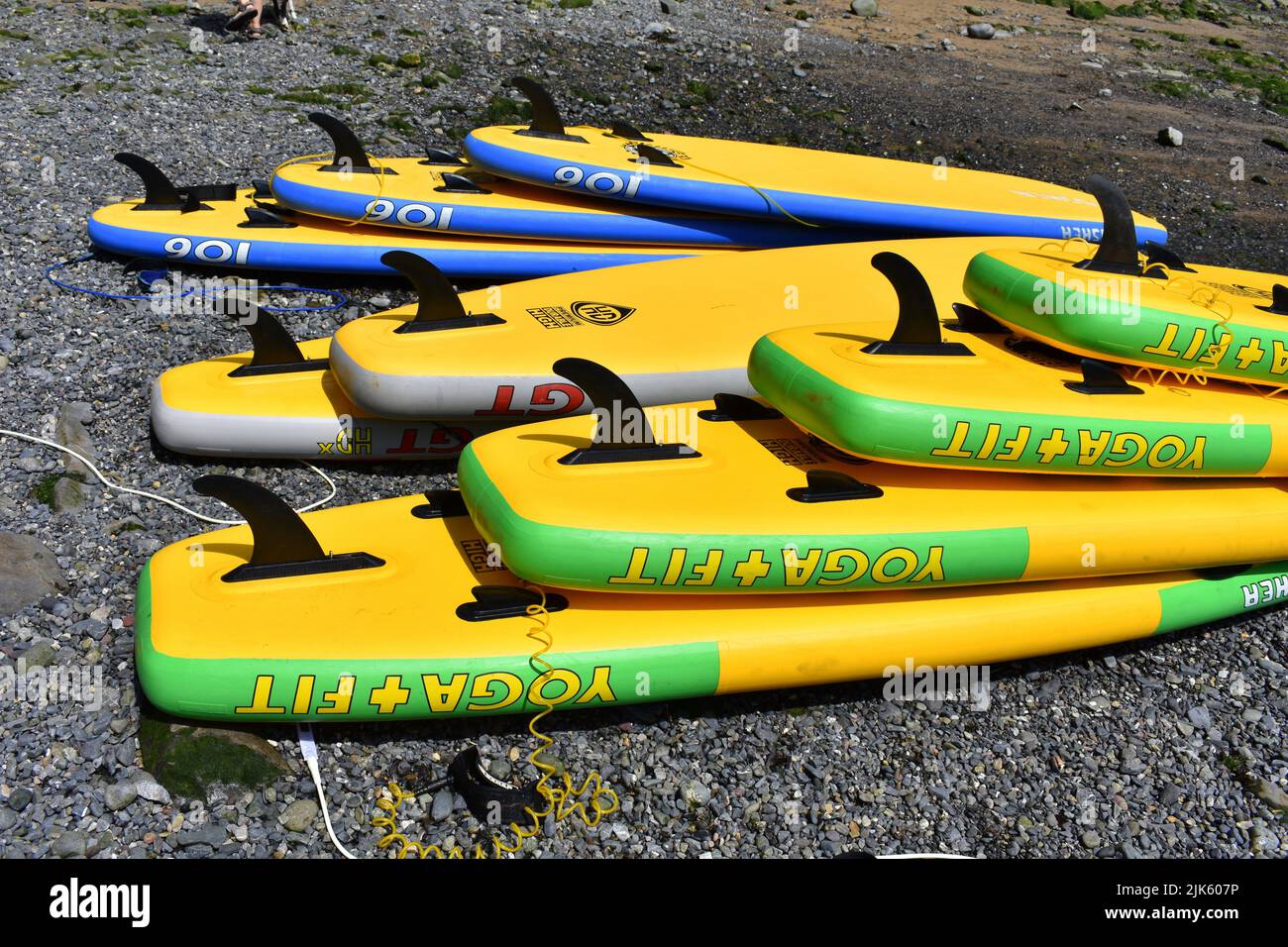 Gelbe Stand Up Paddle Boards, gestapelt am Strand, Stackpole Quay, Stackpole, Pembrokeshire, Wales Stockfoto