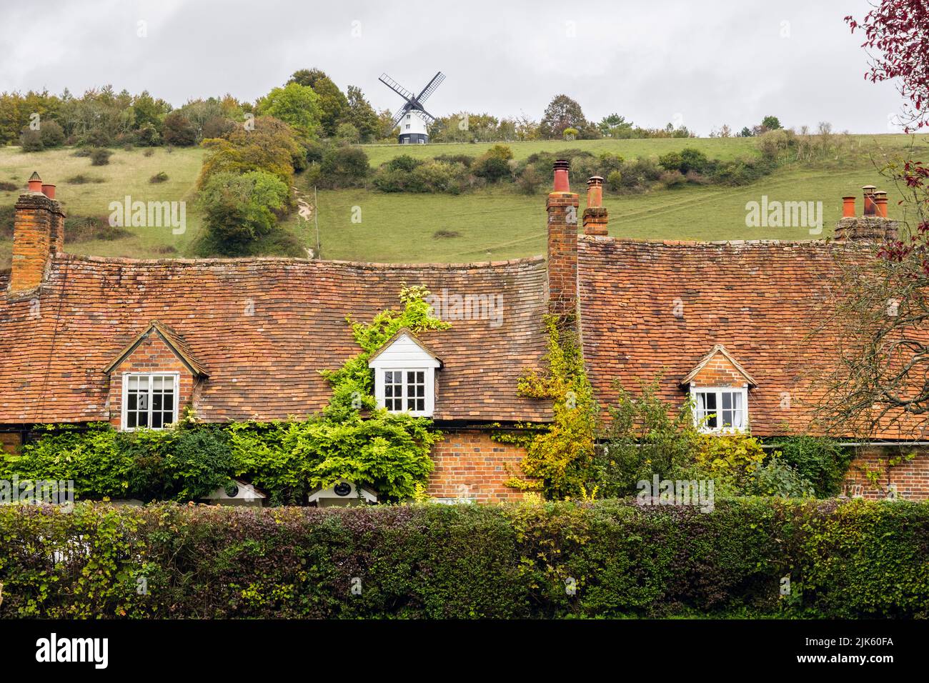 Historische alte Häuser unterhalb von Turville Hill mit Windmühle im Dorf. Turville, Buckinghamshire, England, Großbritannien. Ein malerisches Dorf in Chiltern Hills Stockfoto