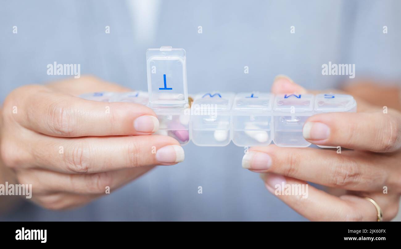 Das hilft mir, mich daran zu erinnern, welche Pillen ich nehmen sollte. Eine ältere Frau hält ihre wöchentliche Pillenbox. Stockfoto