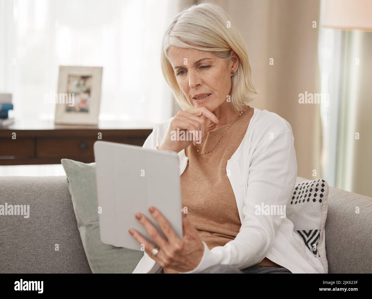Wenn Sie nicht wissen, informieren Sie sich. Eine reife Frau mit einem digitalen Tablet und sieht besorgt zu Hause. Stockfoto