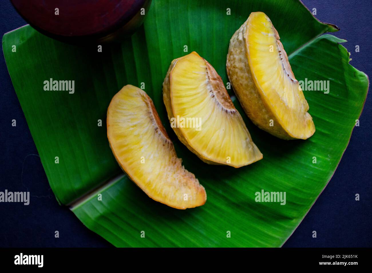 sukun Goreng oder gebratene Brotfrucht serviert auf Bananenblatt auf schwarzem Hintergrund Stockfoto