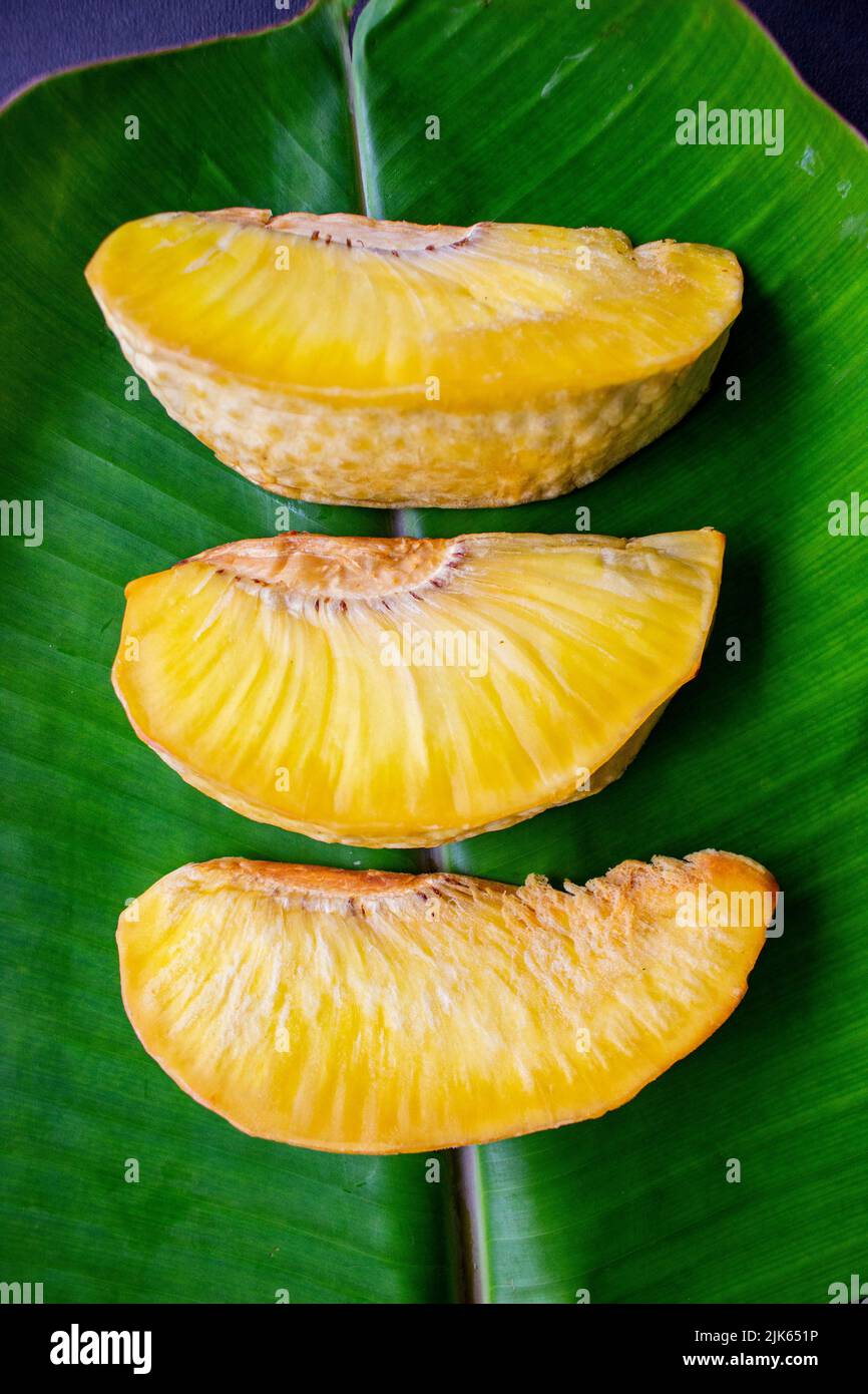 sukun Goreng oder gebratene Brotfrucht serviert auf Bananenblatt auf schwarzem Hintergrund Stockfoto