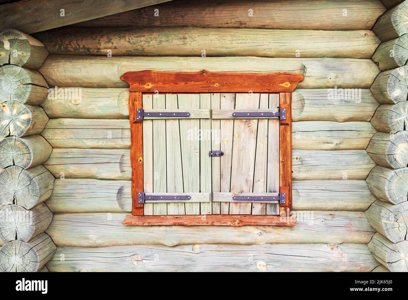 Rundes Blockhaus mit offenen Fensterläden aus Holz mit Metallscharnieren Stockfoto