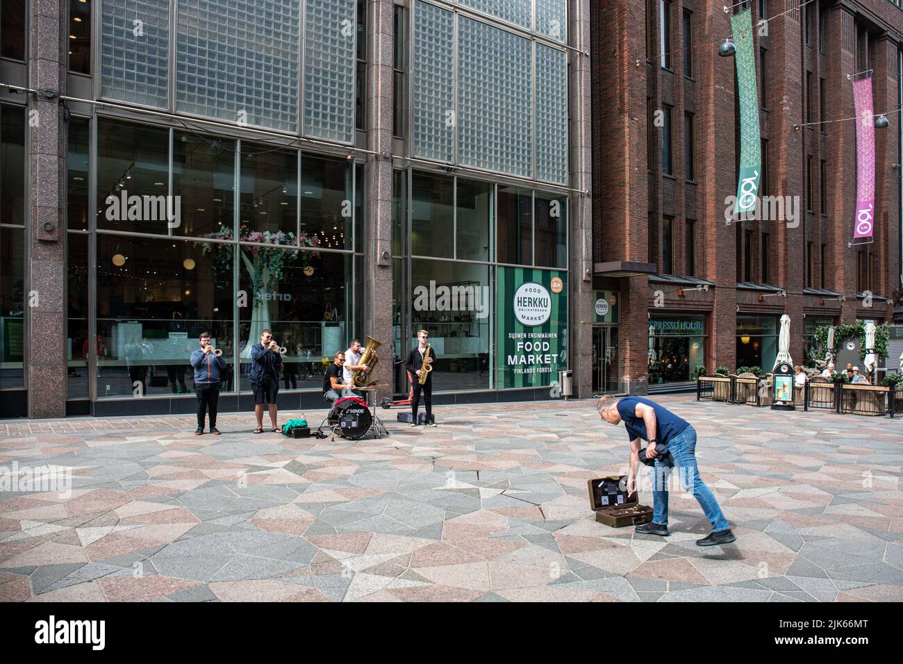 Passant, der in Keskuskatu, Helsinki, Finnland, Geld im Koffer von Straßenmusikern ablässt Stockfoto