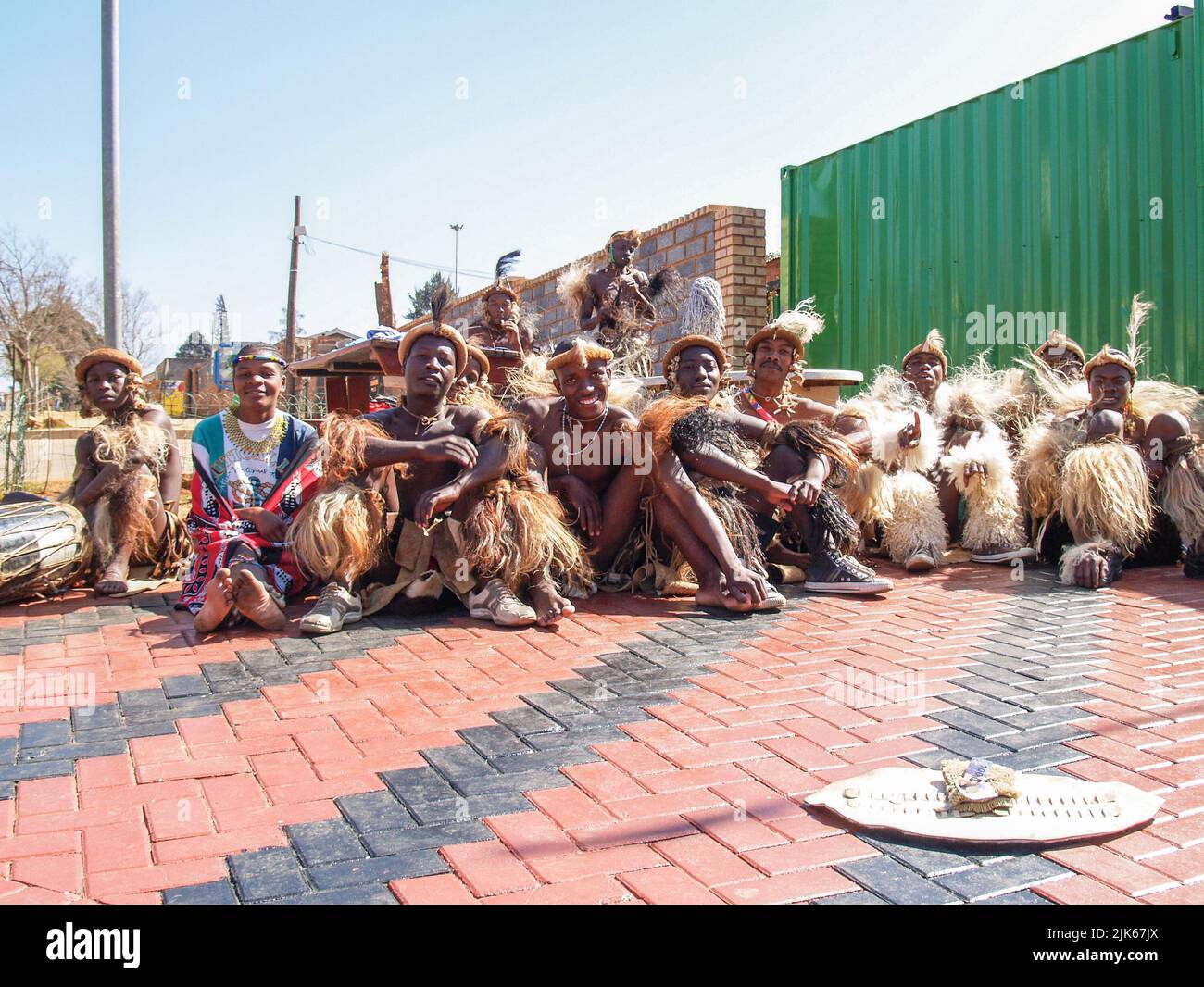 Johannesburg Südafrika - August 15 2007; Gruppe von Straßenkünstlern in traditioneller Tracht, die zusammen mit ihrem Sammelschild sitzen Stockfoto