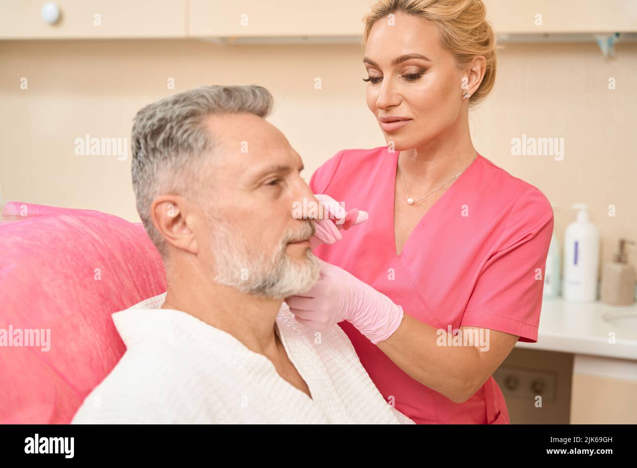 Attraktive Frau Kosmetologin, die dem Mann im Sessel eine Schönheitsspritze gibt Stockfoto