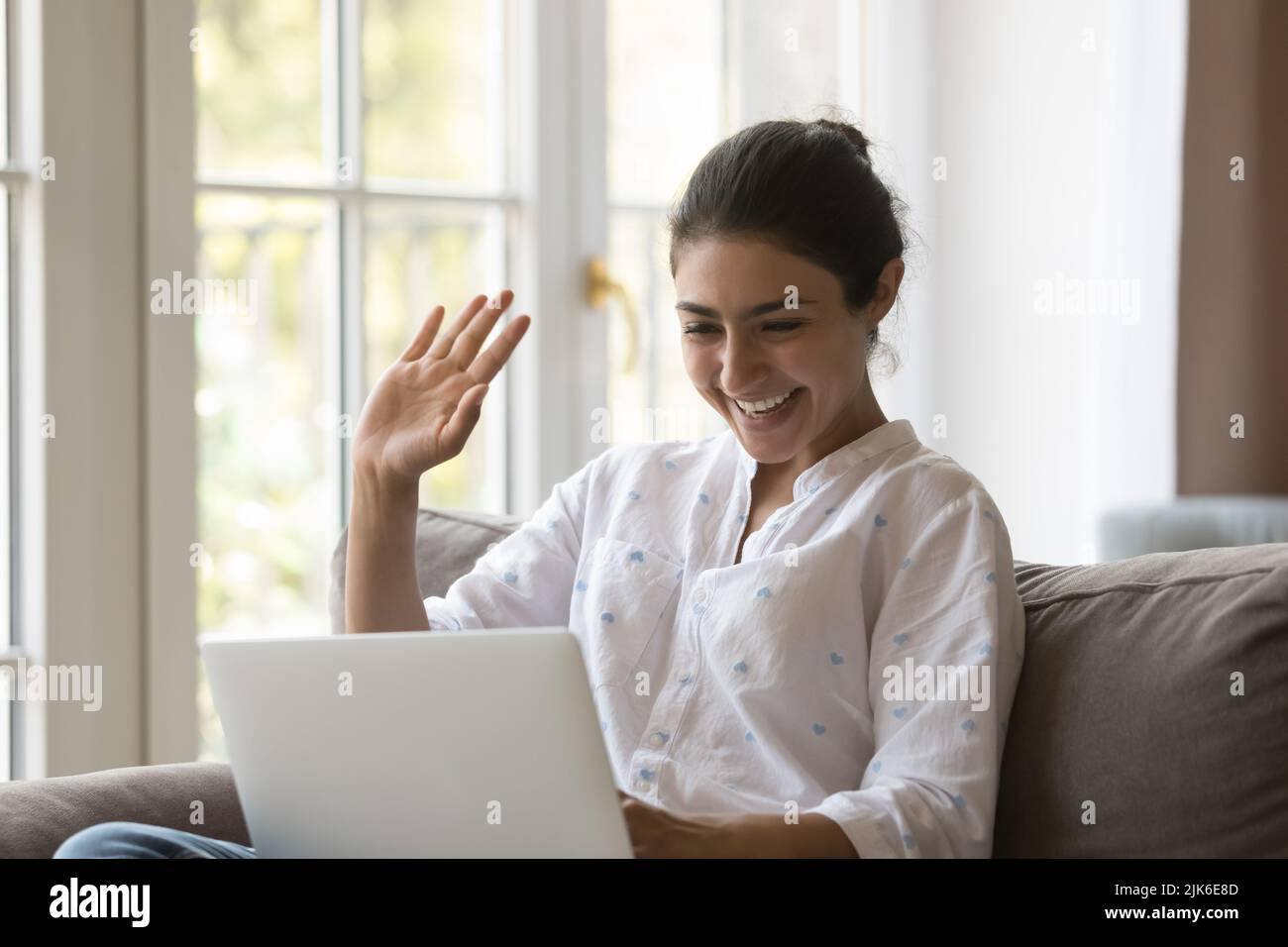 Fröhliche positive indische Laptop-Benutzer Frau winkt Hand Hallo Stockfoto