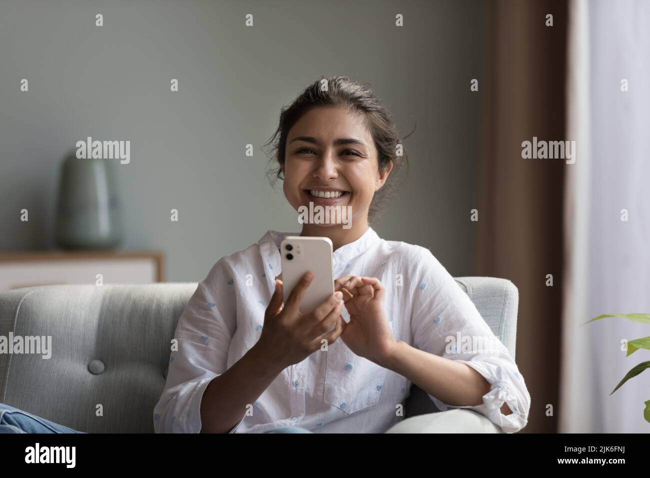 Glückliche schöne tausendjährige indische Frau mit Smartphone Stockfoto