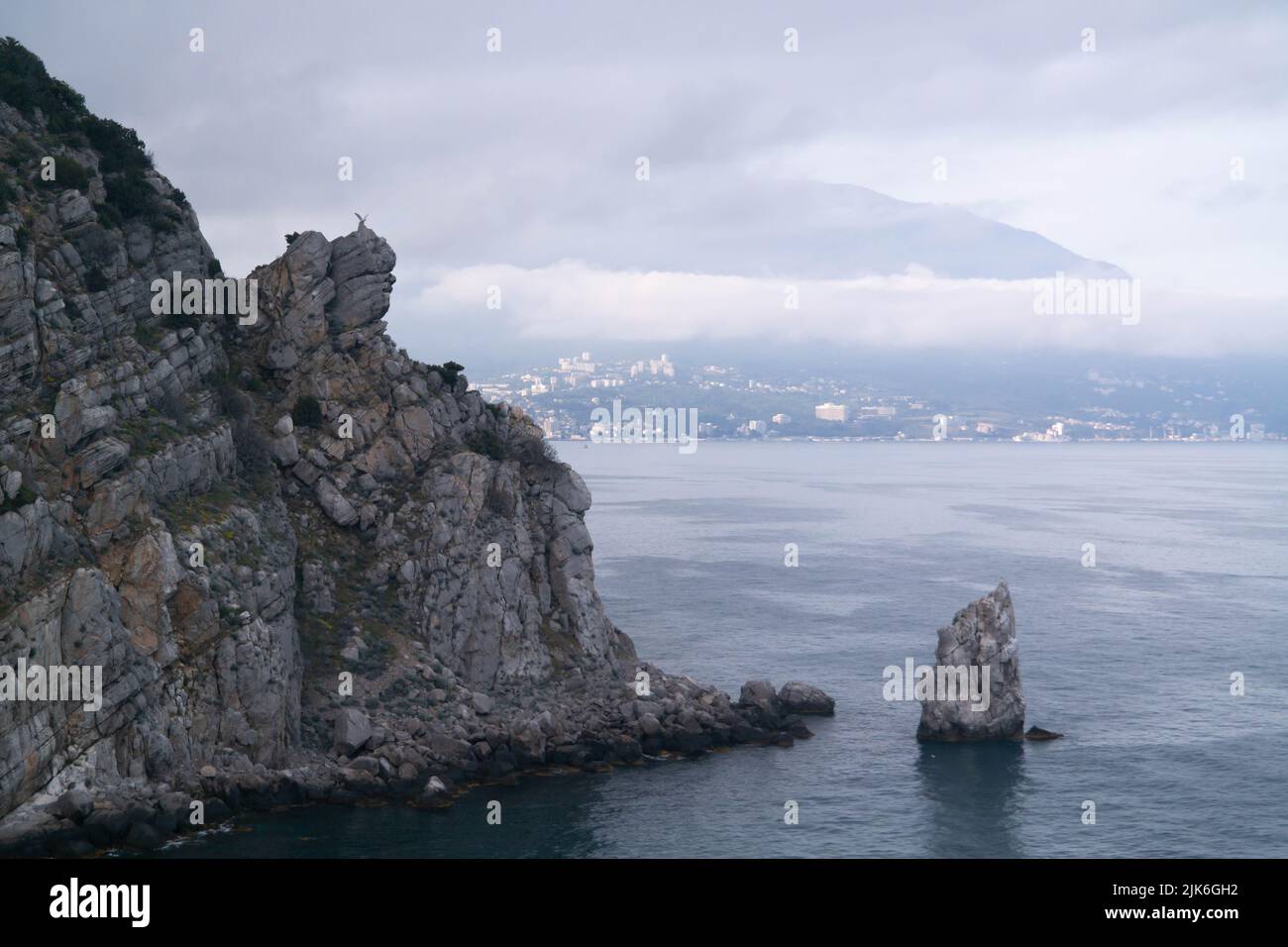 Ein Felsen im Meer mit einem Adler auf der Oberseite und einem segelförmigen Felsen am Fuß. Stockfoto