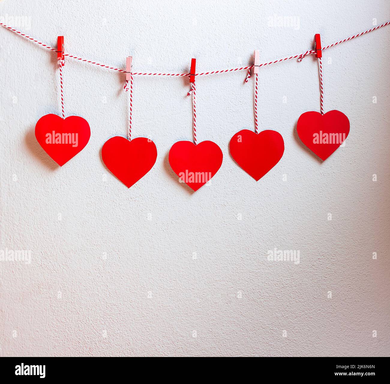 Rotes Herz Papier geschnitten mit natürlicher Kordel und roten Clips an der Wand hängen, Kopierraum, Valentinstag - Bild Stockfoto