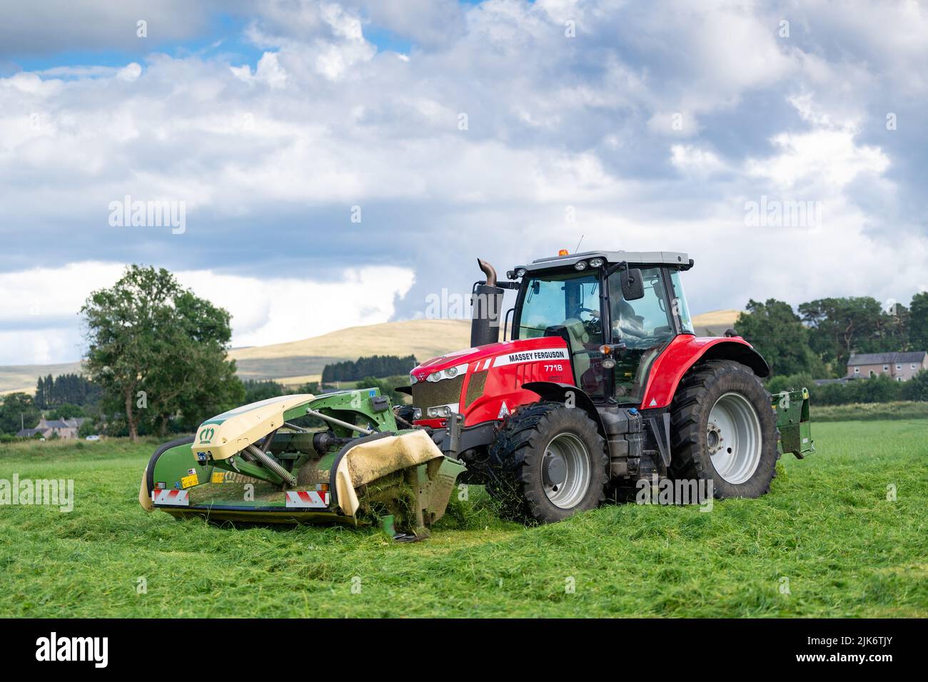 Mähen einer Silagewiese mit einem Massey Ferguson 7718 Traktor und einer vorne und seitlich montierten Krone Mähkombination. Cumbria, Großbritannien. Stockfoto