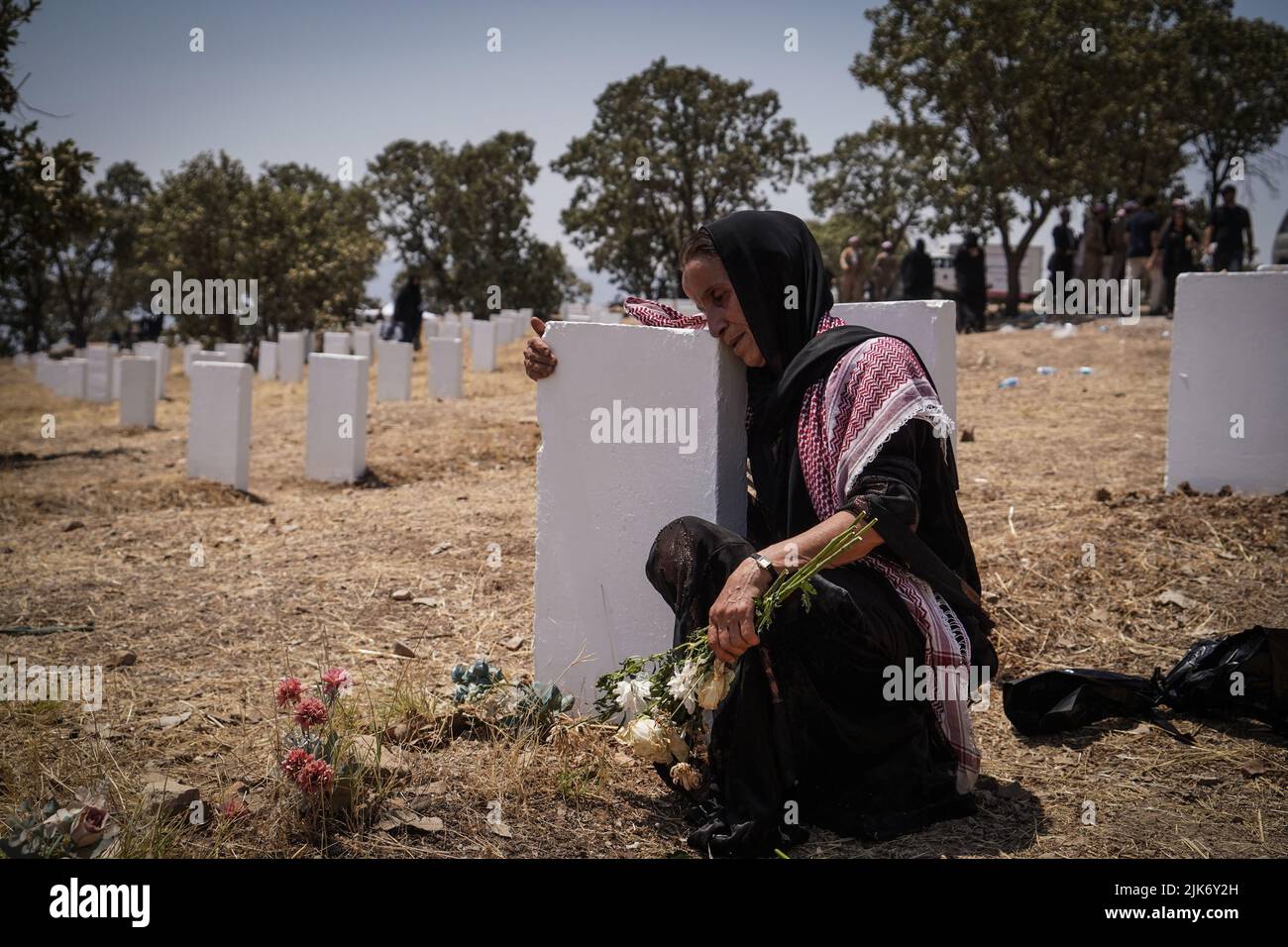 Barzan, Irak. 31.. Juli 2022. Eine ältere kurdische Frau trauert am Grab auf dem Anfal-Friedhof, nachdem die Überreste von 100 Barzani-Opfern begraben wurden, die Ende 1980s bei den Anfal-Operationen getötet wurden. Das Regime des baathistischen Irak unter Führung von Saddam Hussein hat Ende 1980s gewalttätige Operationen gegen die Kurden durchgeführt, bei denen mindestens 182.000 Tote und 90 % der kurdischen Dörfer zerstört wurden. Quelle: Ismael Adnan/dpa/Alamy Live News Stockfoto