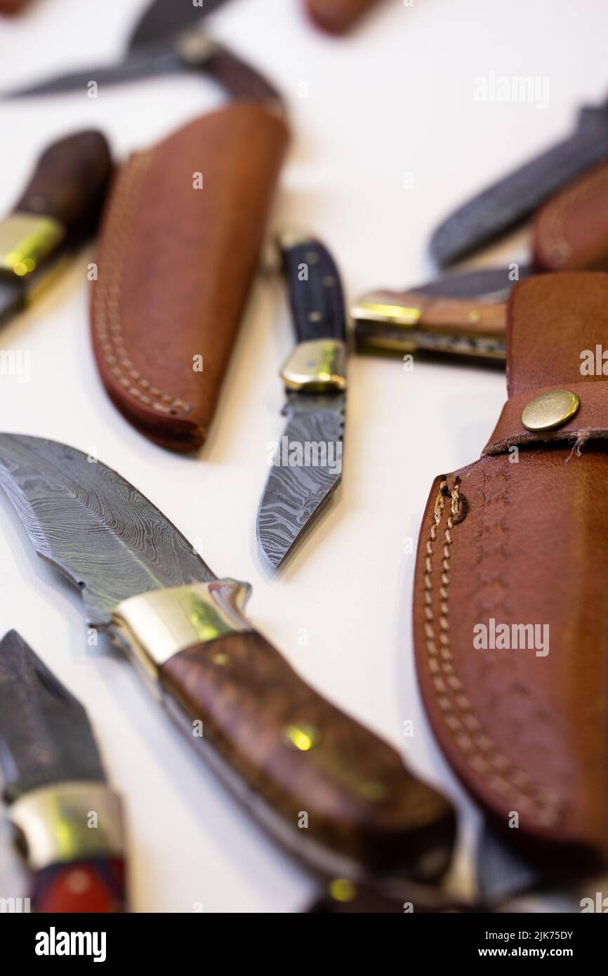 Verschiedene Messer und Lederetuis auf weißem Hintergrund Stockfoto