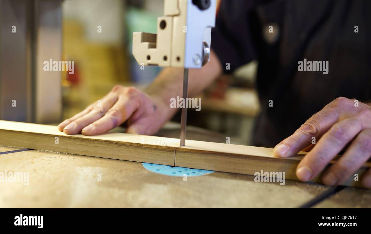 Handarbeit, Tischlerei Konzept, Holzbearbeitung. Zimmermann, der in einem Fabrikatelist arbeitet. Tischler schneidet Holzbrett auf Stichsägemaschine. Stockfoto