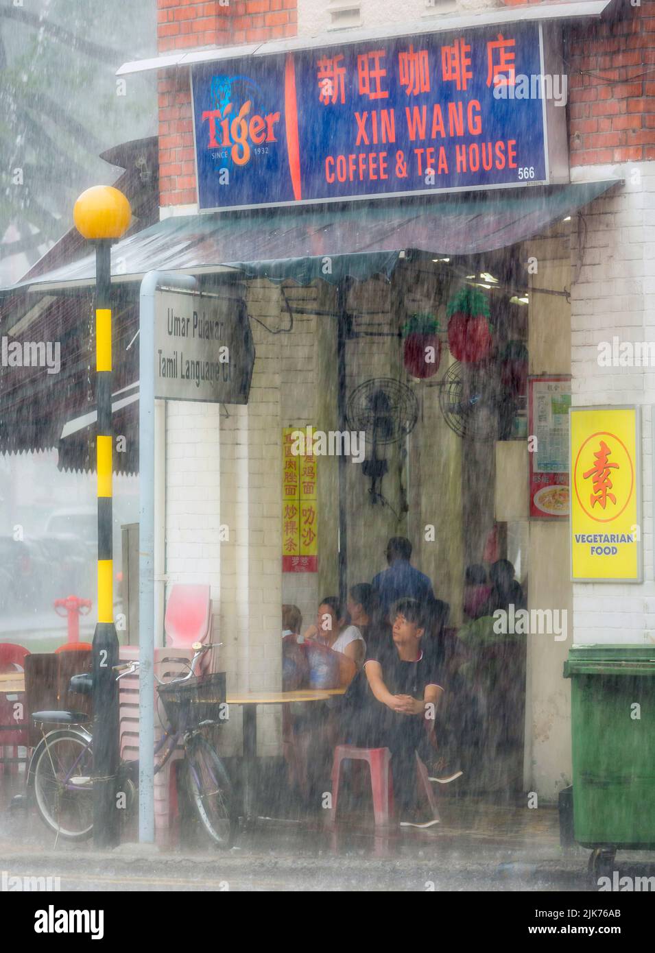 Kunden im Kaffee- und Teehaus warten auf tropischen Regenguss auf der Serangoon Road, Republik Singapur. Stockfoto