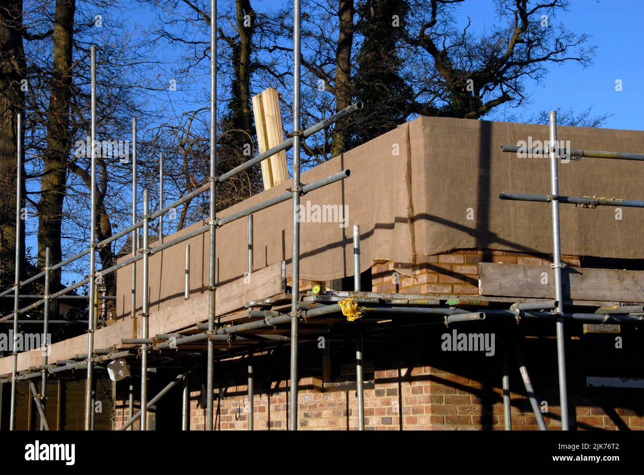 Hessisch umwickelt neue Mauerwerk im Hausbau, um im Winter vor Frost über Nacht zu schützen Stockfoto