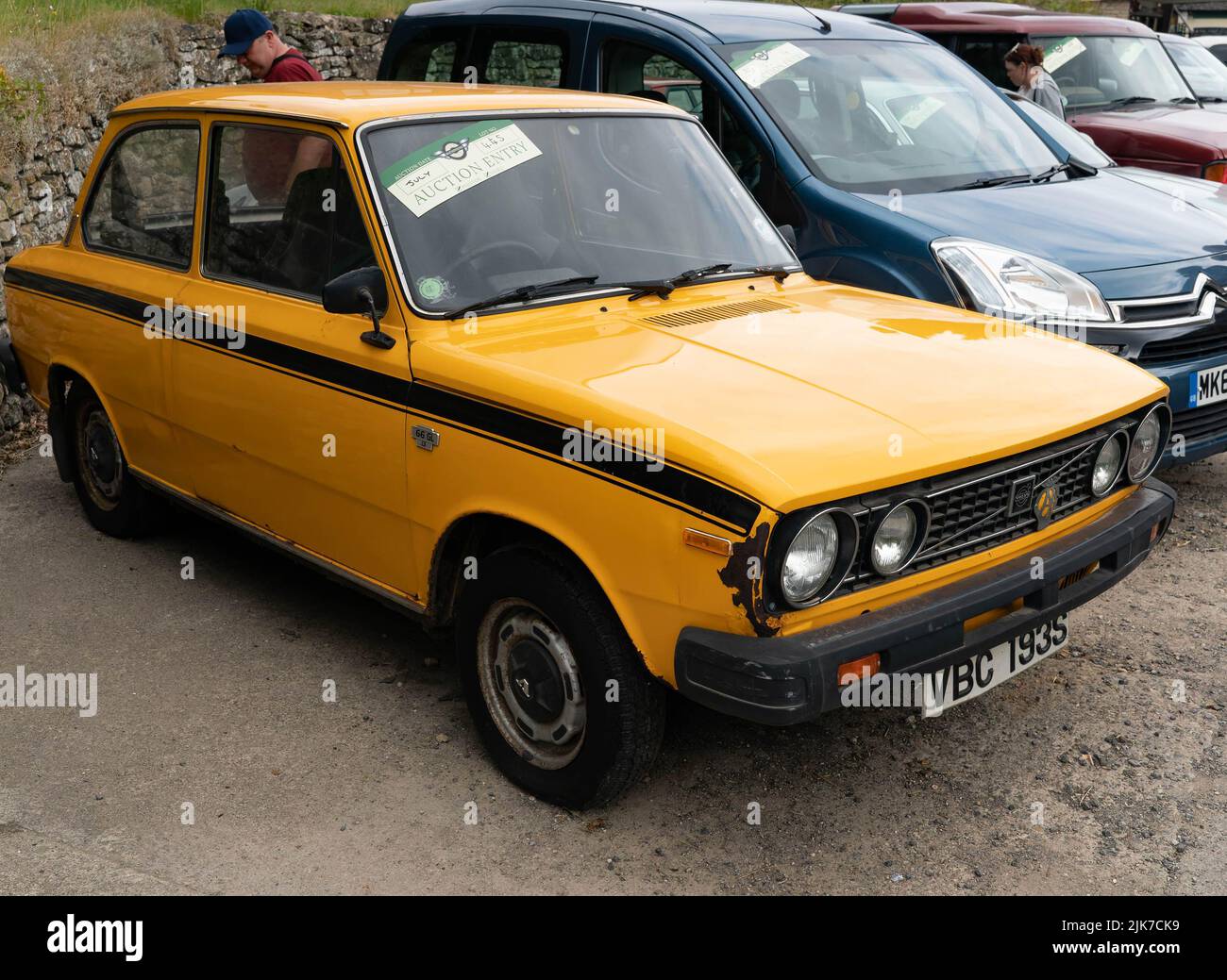 Hellgelbes klassisches Datsun-Limousine auf der Oldtimer-Ausstellung mit Steinmauern Stockfoto