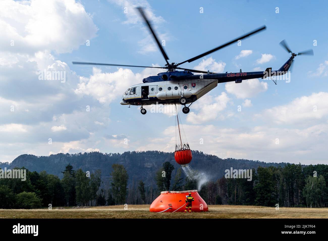 Mezni Louka, Tschechische Republik. 31.. Juli 2022. Der slowakische Hubschrauber bringt Wasser aus einem speziellen 54,5-Kubikmeter-Beutel, der sich in der Nähe des Feuers befindet und von Tankern in der Nähe von Mezni Louka, Hrensko, im Nationalpark Ceske Svycarsko (Tschechische Schweiz), Tschechische Republik, gefüllt wird, in den Eimer, 31. Juli 2022. Das Feuer im Nationalpark Tschechische Schweiz dauert seit acht Tagen an. Quelle: Ondrej Hajek/CTK Photo/Alamy Live News Stockfoto